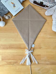 a brown kite sitting on top of a wooden floor next to stuffed animals and books