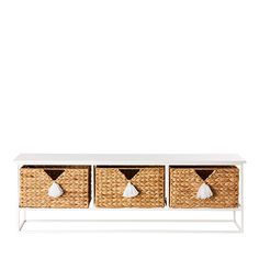 three wicker baskets with tassels sit on a white shelf