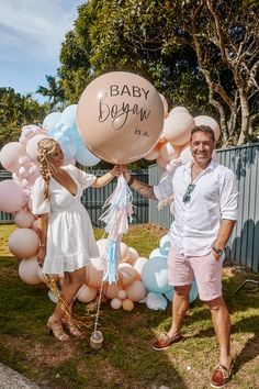 a man and woman holding balloons with the words baby boy written on them in pink