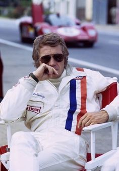 a man sitting in a white chair next to a race car