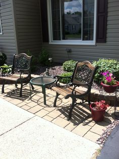 three wooden chairs sitting on top of a patio next to a table and potted plants