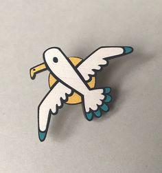 a white and blue bird with yellow wings on it's back lapel pin