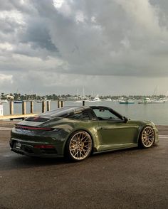 a green sports car parked in front of a body of water