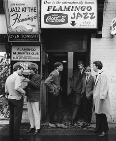 black and white photograph of men standing in front of a building with signs on it