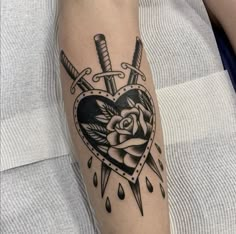 a heart with two swords and a rose tattoo on the arm, done by person