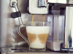 coffee being poured into a glass in front of an espresso machine