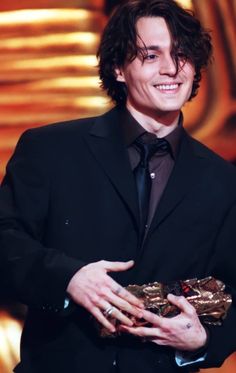 a man in a suit and tie is holding a gold object with his right hand