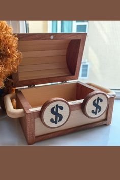 a teddy bear sitting next to a wooden box with dollar signs on the inside and sides