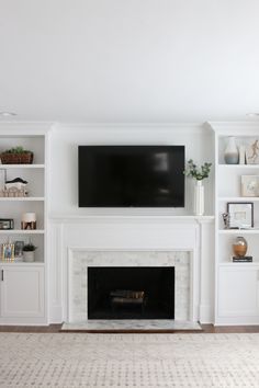 a living room with white bookcases and a fireplace