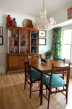 a dining room table with blue chairs and a china cabinet