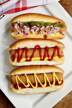 two hot dogs with ketchup, mustard and relish on a white plate