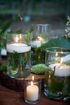 candles and moss in glass vases on a table