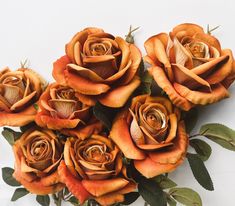 a bunch of orange roses with green leaves