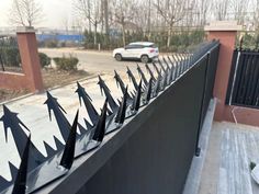 a car is parked on the side of a road behind a fence with black spikes