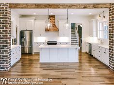 an open kitchen with white cabinets and wood flooring is pictured in this image, there are two pendant lights hanging from the ceiling