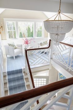 an overhead view of a staircase leading to a living room with white furniture and chandelier