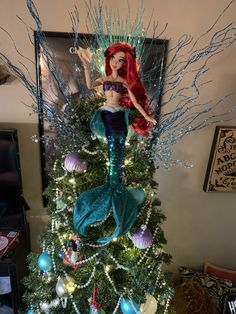 the little mermaid is sitting on top of the christmas tree