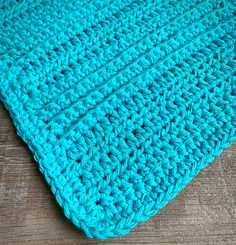 a blue crocheted blanket laying on top of a wooden floor