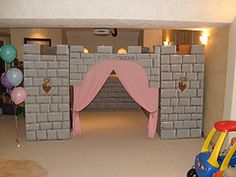 a castle made out of cinder blocks with balloons on the floor and decorations around it