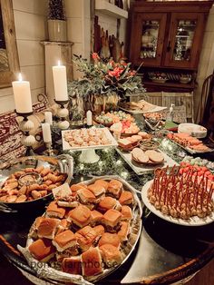 a table filled with lots of food on top of a wooden table next to candles