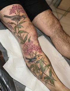 a man's leg with flowers and birds tattooed on the side of his arm