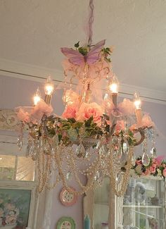 a chandelier hanging from the ceiling with flowers and candles on it's side