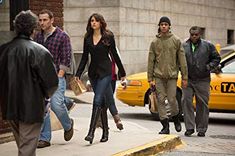 a group of people walking down the street in front of taxi cabs and taxis