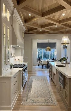 a large kitchen with white cabinets and wood ceilinging, along with an area rug on the floor