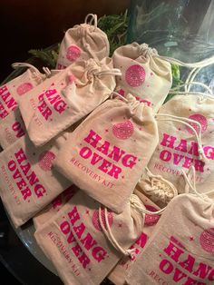 several bags with pink lettering on them are sitting on a glass plate next to some plants