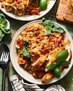 two plates of pasta with spinach and tomato sauce