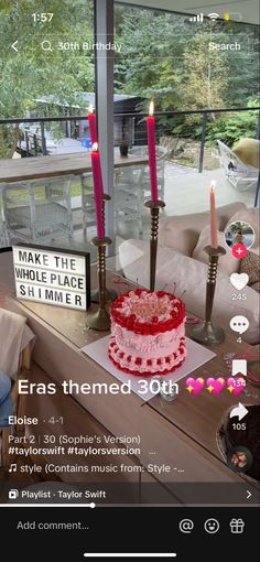 a red and white cake sitting on top of a wooden table next to two candles