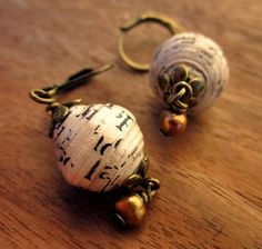 two white and gold earrings sitting on top of a wooden table next to each other