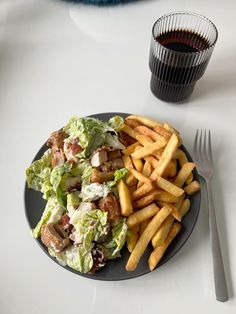 a plate with french fries, lettuce and meat on it next to a cup of wine