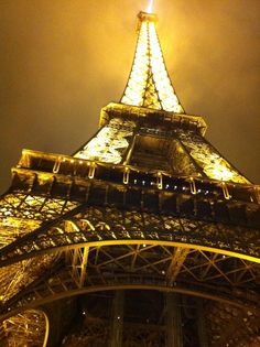 the eiffel tower lit up at night with lights on it's sides