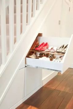 an open drawer underneath a staircase with shoes in it