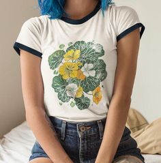 Nasturtium Blooms Ringer Tee - a harmonious blend of botanical beauty and retro style. Crafted from soft, breathable cotton, this ringer tee features a stunning block print image of Nasturtium leaves and flowers, adding a touch of nature-inspired elegance to your day. Admire the detailed and beautifully crafted block print image, capturing the intricate details and vivid colors of Nasturtium blooms. This tee combines the artistic appeal of traditional printmaking with the comfort of modern fashion. Searching for a unique and thoughtful gift? This Nasturtium Blooms Ringer Tee is the ideal choice for plant enthusiasts, gardeners, and anyone who appreciates the beauty of botanical designs. Surprise a friend or loved one with a gift that celebrates their love for both nature and artistry. Whet Retro Print Tops, Tabitha Swatosh Flower Shirt, Nasturtium Leaves, Retro Flower Print, Ringer Shirt, Mama Style, Botanical Beauty, Ringer Tee, Playing Dress-up