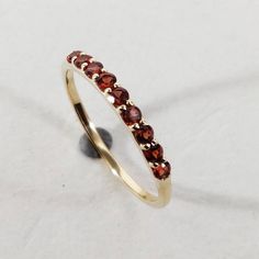 This stunning half eternity ring is set in 14k Solid Yellow Gold with Natural Garnet with utmost precision. It is an unique statement gemstone ring for nearly every occasion and is completely hassle-free jewelry. 🔷ABOUT GEMSTONE:  Garnet is often associated with boosting energy levels and enhancing physical strength. It's believed to help combat fatigue and increase endurance, making it a popular choice among athletes and those with physically demanding lifestyles. Garnet is sometimes associate January Birthstone Rings, Alternative Engagement Ring, Diamonds Necklace, Garnet Gem, Bracelet Wedding, London Blue Topaz Ring, Blue Topaz Stone, Garnet Jewelry, Half Eternity Ring