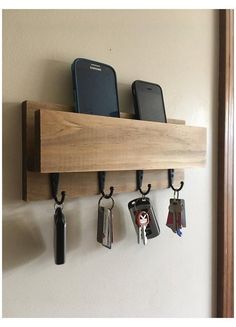 three cell phones are hanging on the wall with key holders attached to it and two keys hang from hooks