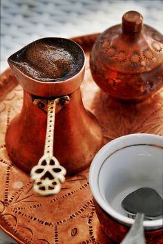 two coffee cups on a tray next to an old fashioned grinder and sugar shaker