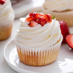 a cupcake with white frosting and a raspberry on top