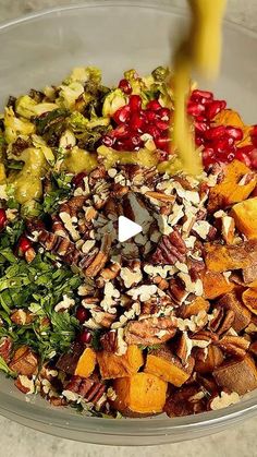 a glass bowl filled with chopped vegetables, nuts and other things to make a salad