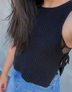 a close up of a person wearing a black shirt and jeans with a cell phone in her hand