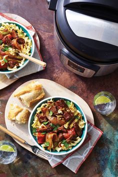 two bowls filled with pasta and meat on top of a table next to an air fryer