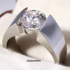 a close up of a ring with a diamond in it on a white cloth background