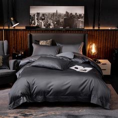 a large bed in a bedroom with grey sheets and pillows