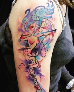 a woman's arm with a colorful watercolor tattoo design on her left shoulder