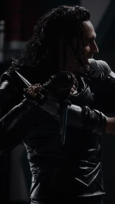 a man with long hair and leather gloves on holding onto another person's shoulder