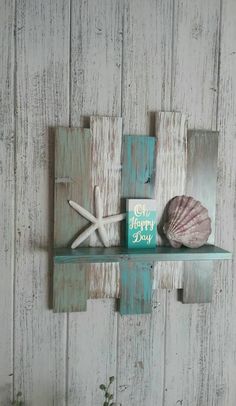 a wooden shelf with two seashells and a happy day card on it, against a white painted wood wall