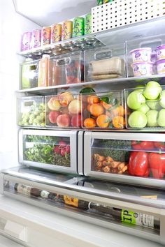 an open refrigerator filled with lots of fresh fruit and veggies in plastic containers