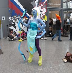 a woman with blue hair and makeup is dressed in costume